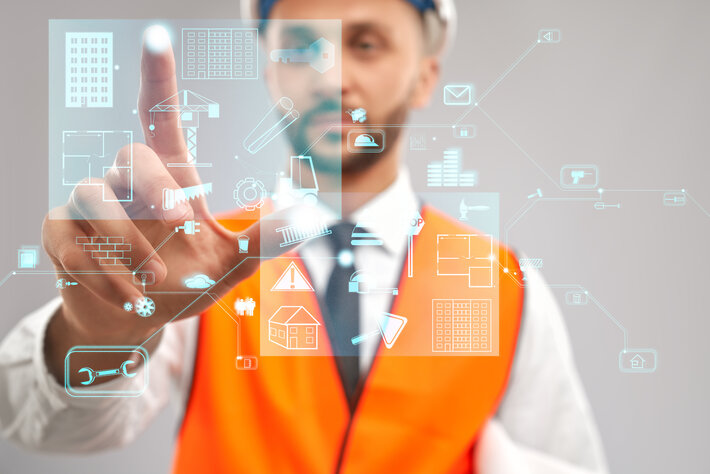 Close up of architect wearing reflective vest and helmet. Selective focus of digital tactile charts screen, man touching virtual icon on projection. Concept of digitalization, construction.