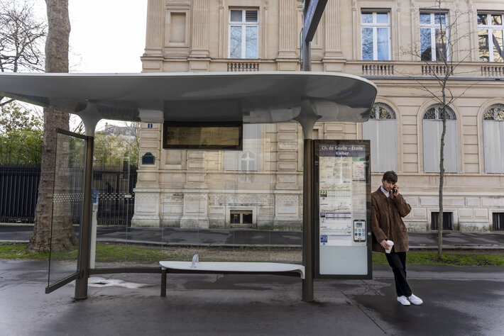 young french man waiting station bus talking smartphone
